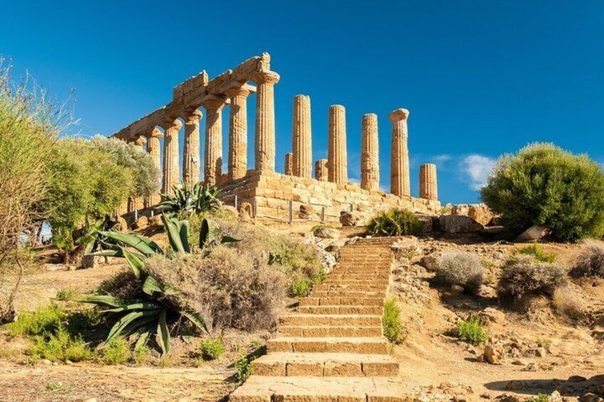 Ancient ruins with columns and steps leading up to them. 1