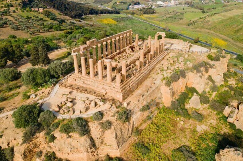 An ancient ruin with columns, surrounded by greenery and hills. 3