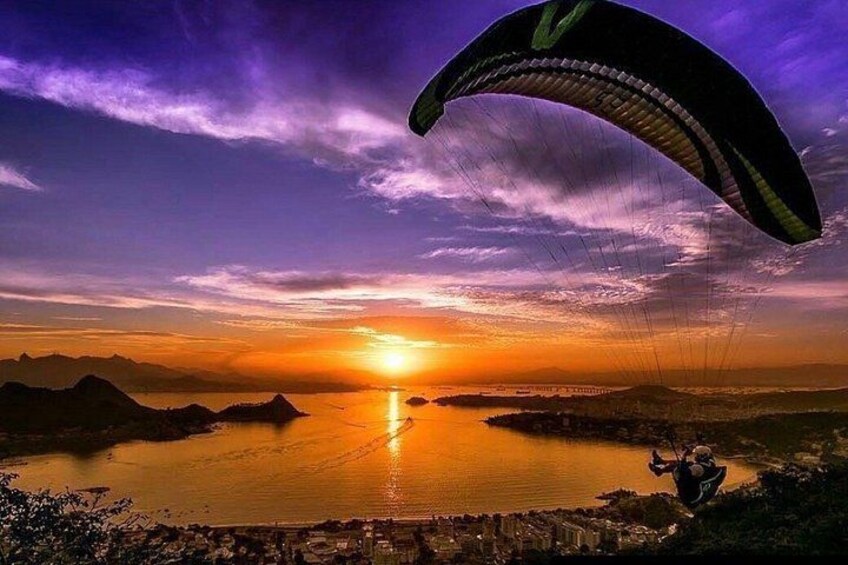 A sunset over a body of water with a person paragliding. 5