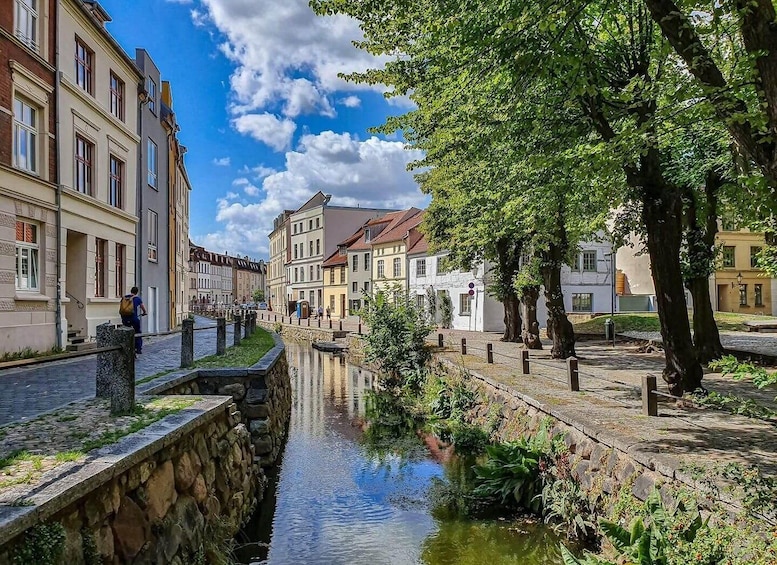 A canal with buildings on one side and trees on the other. 5