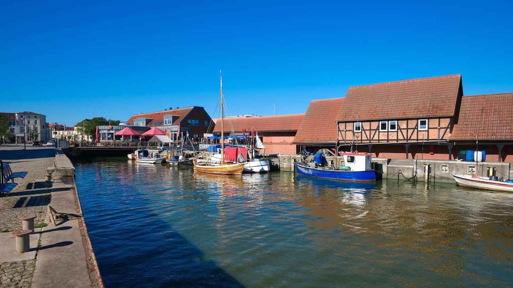 A harbor with boats docked, buildings with red roofs, and a clear blue sky. 3