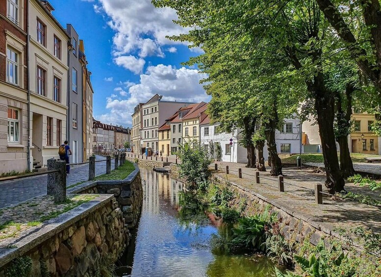 A canal with buildings on one side and trees on the other. 2