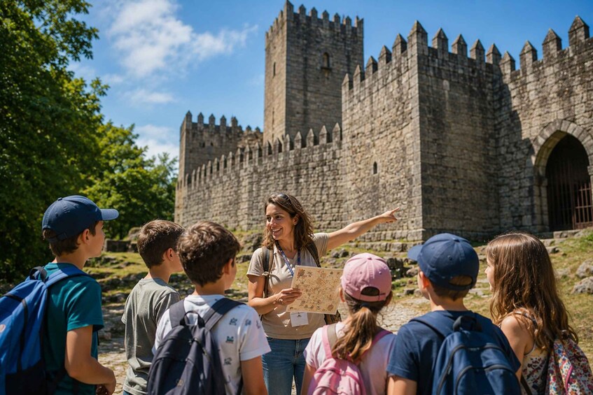 A group of people with a guide pointing towards a historic stone castle. 1