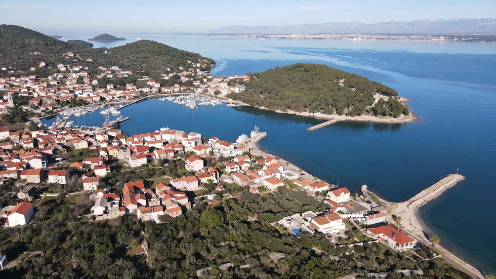 A coastal town with red-roofed houses, a marina, and a peninsula with dense greenery. 2