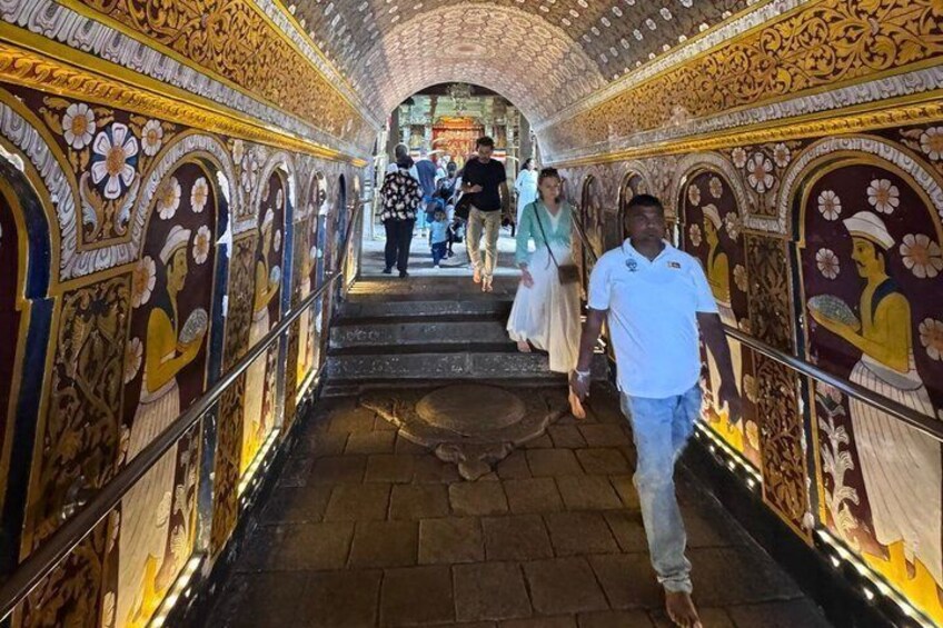 A corridor with ornate murals and a tiled ceiling. 3