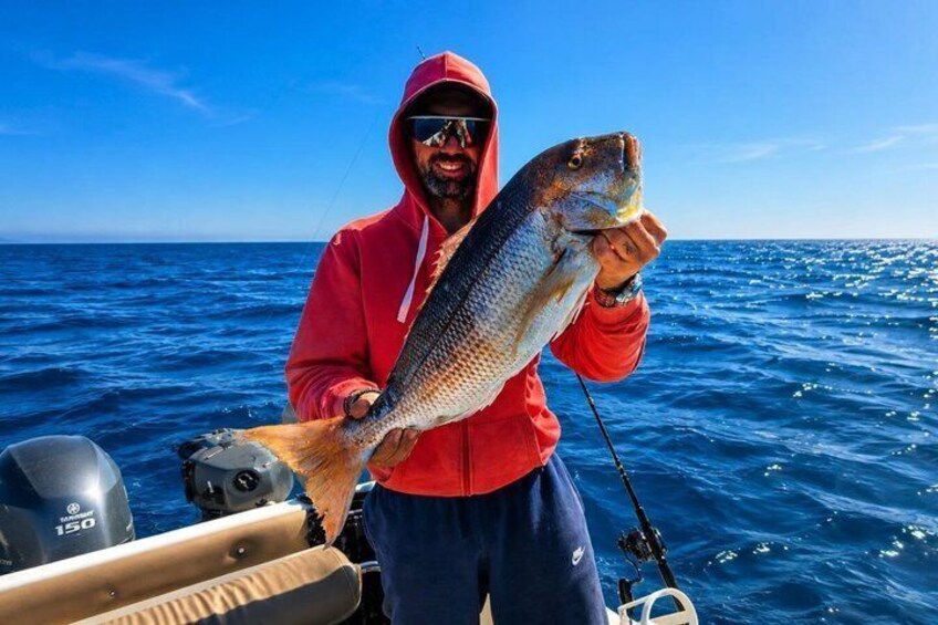 A person holding a fish on a boat in the ocean. 2