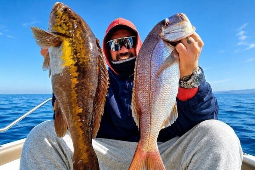 A person holding two fish on a boat with a clear blue sky in the background. 4