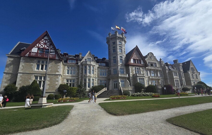 A large, historic building with a prominent tower and multiple flags. 2