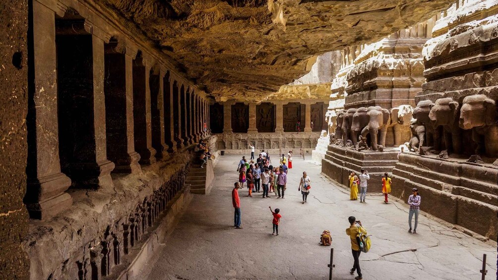 An ancient cave temple with columns and elephant sculptures. 4