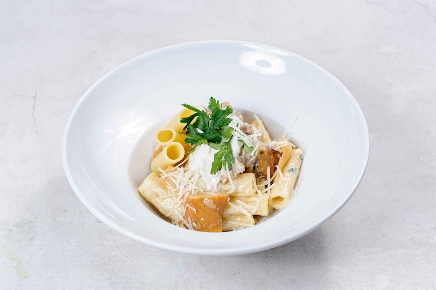 A bowl of pasta with a creamy sauce, garnished with parsley and grated cheese. 2