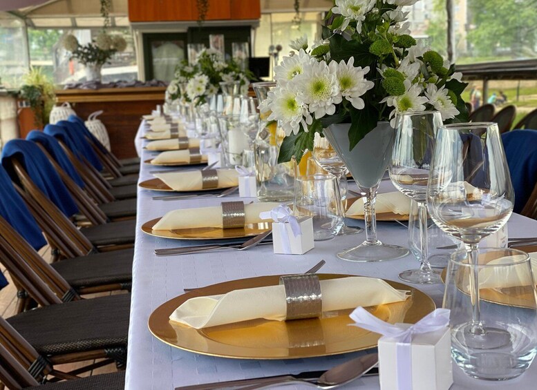 A long table set for a formal event with white flowers, gold plates, and clear wine glasses. 5