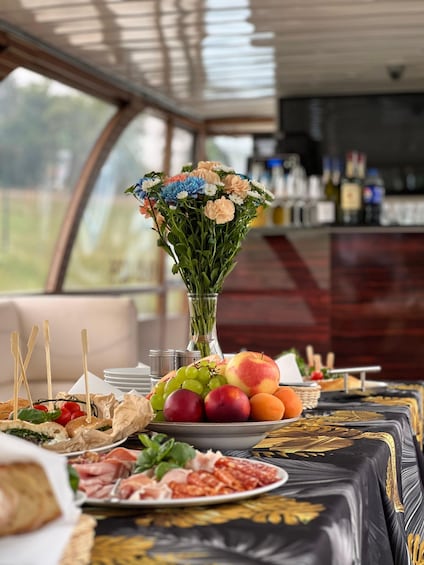 A table with food, a vase of flowers, and a view of the outdoors. 4