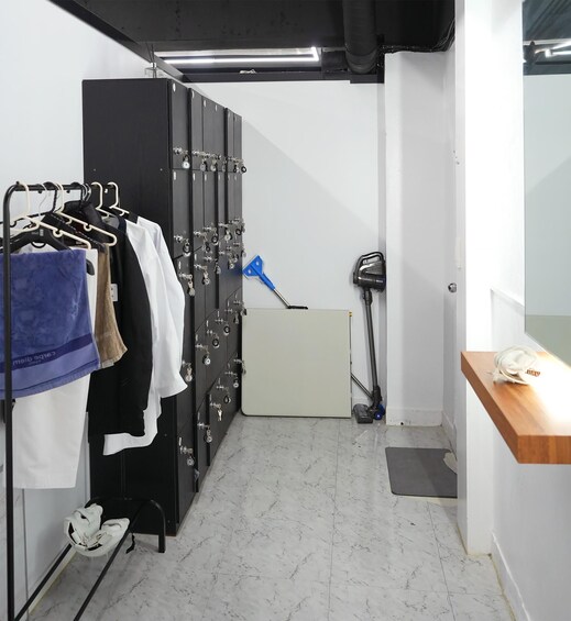 A room with a black metal cabinet with keys, a vacuum cleaner, and a wooden table with a white object on it. 3