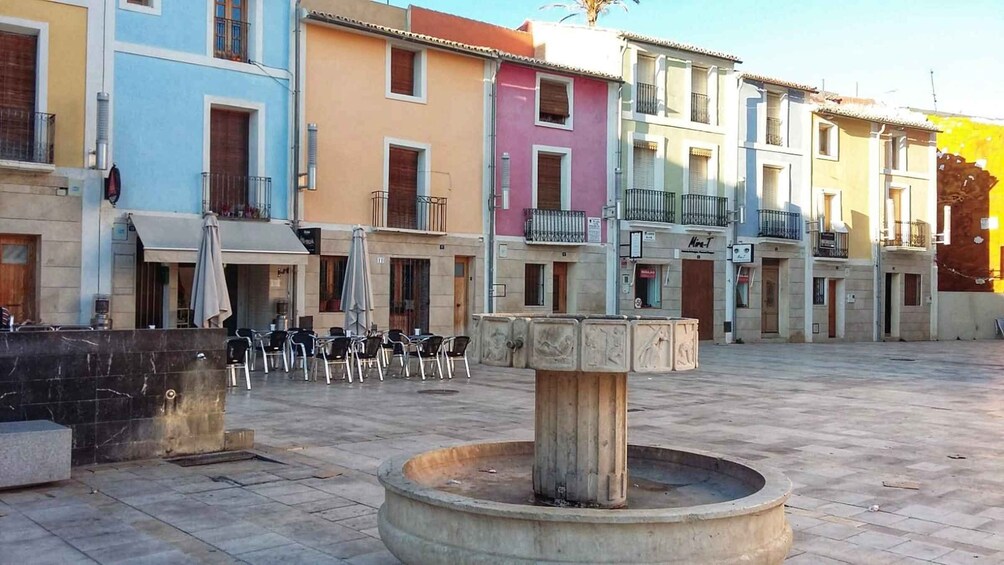 A courtyard with a fountain, outdoor seating, and colorful buildings. 5