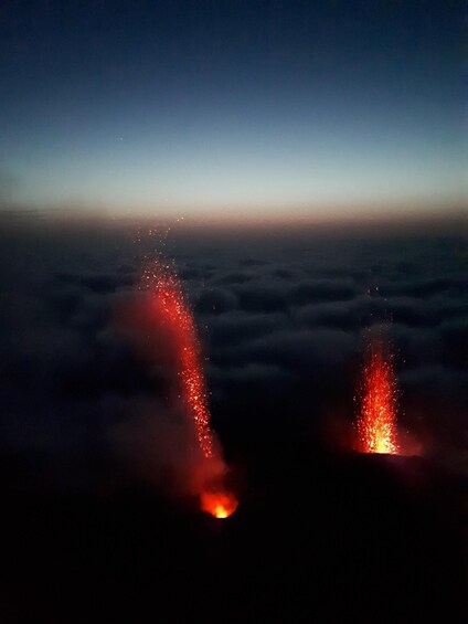 A night sky with two bright red lights against a backdrop of clouds. 3
