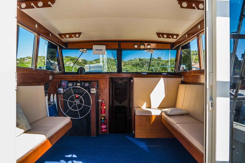 A boat's interior with a steering wheel, control panel, and seating area. 5