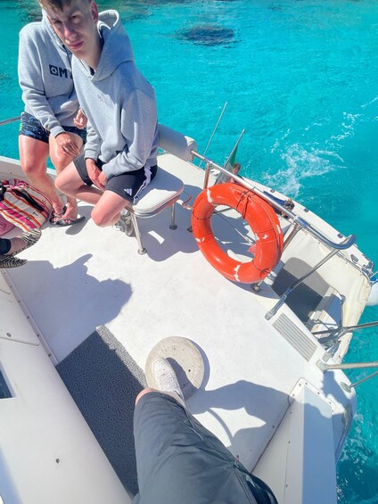 Two people on a boat with a lifebuoy and a wake in the water. 3