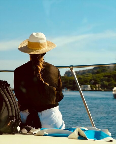 A person with a straw hat sitting on a boat, looking at the water. 1