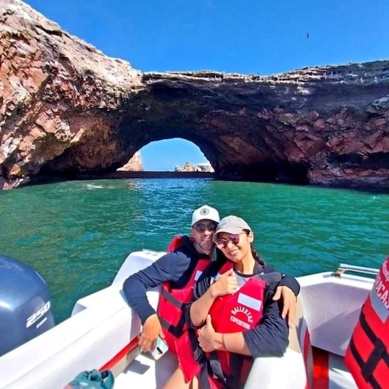 A boat near a rock arch with clear turquoise water. 1