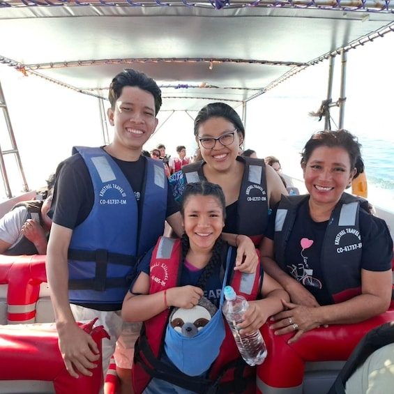 A group of people on a boat wearing life jackets and a child in a sling bag. 3