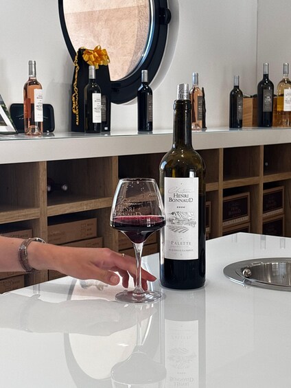 A bottle of Henri Bonneaud 2020 wine and a glass of red wine on a table. 3