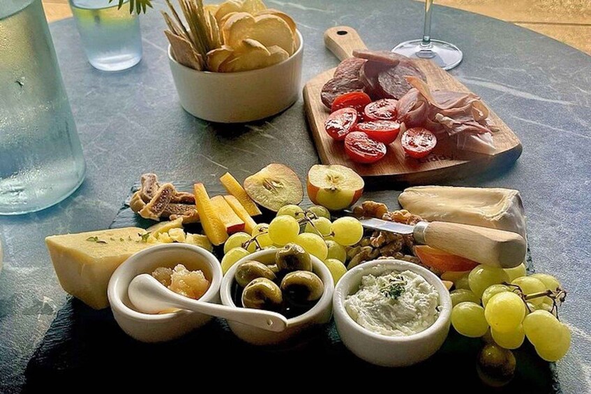 A charcuterie board with cheese, olives, grapes, and various meats. 2