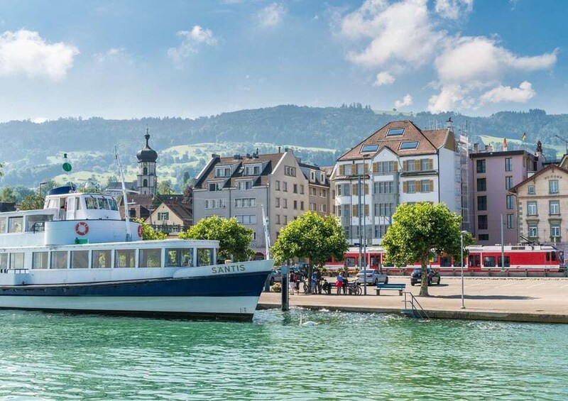 A boat named SANTIS docked at a pier, with buildings and a hill in the background. 2