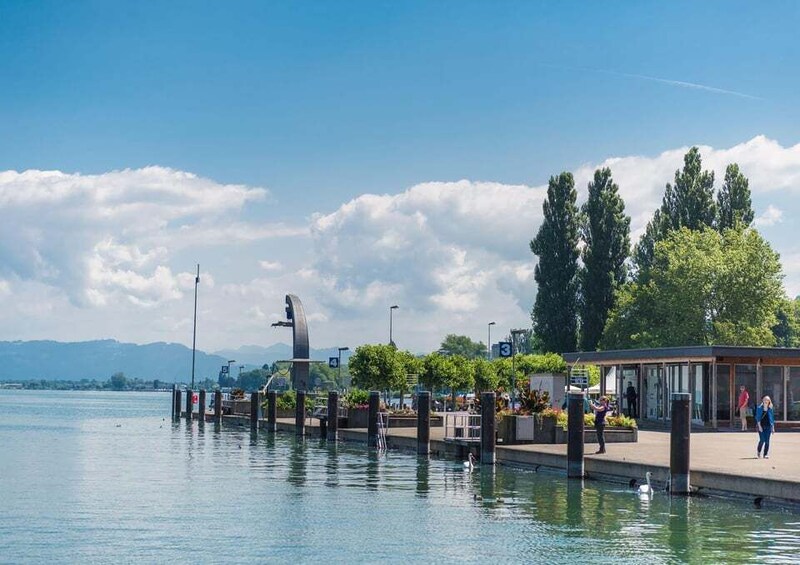 A calm lake with a pier, trees, and a clear sky. 1
