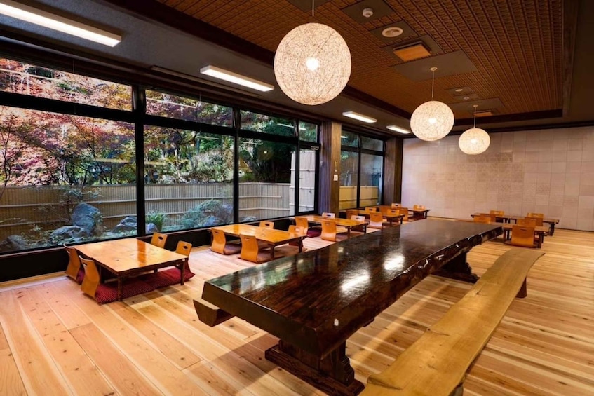 A restaurant with wooden tables and chairs, large windows, and hanging pendant lights. 4