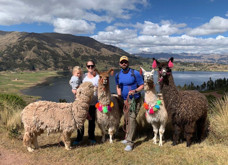 A family with llamas in a mountainous landscape with a lake. 2