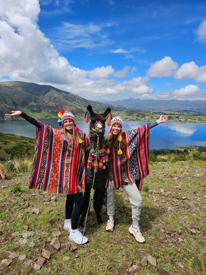 Three people with llama in a mountainous landscape with a lake. 1