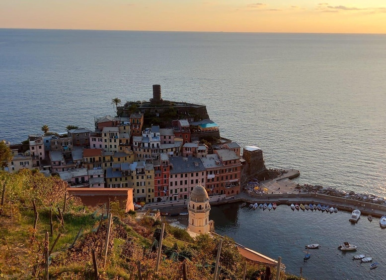A coastal town with colorful buildings, a prominent tower, and boats docked along the waterfront. 1