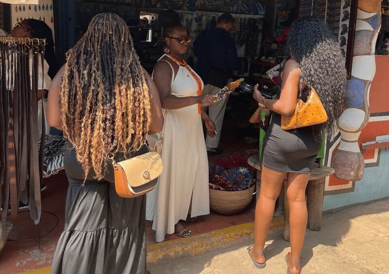 A market with people shopping and a display of colorful textiles. 2