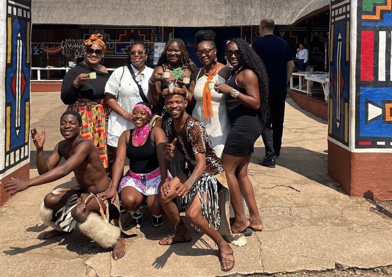 A group of people posing in front of a building with colorful geometric patterns. 1