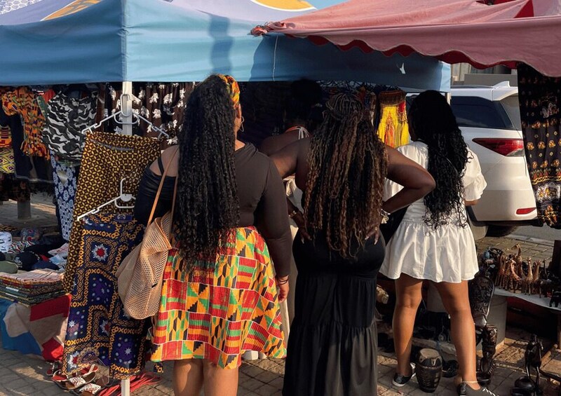 A market stall with colorful fabrics and handbags. 4