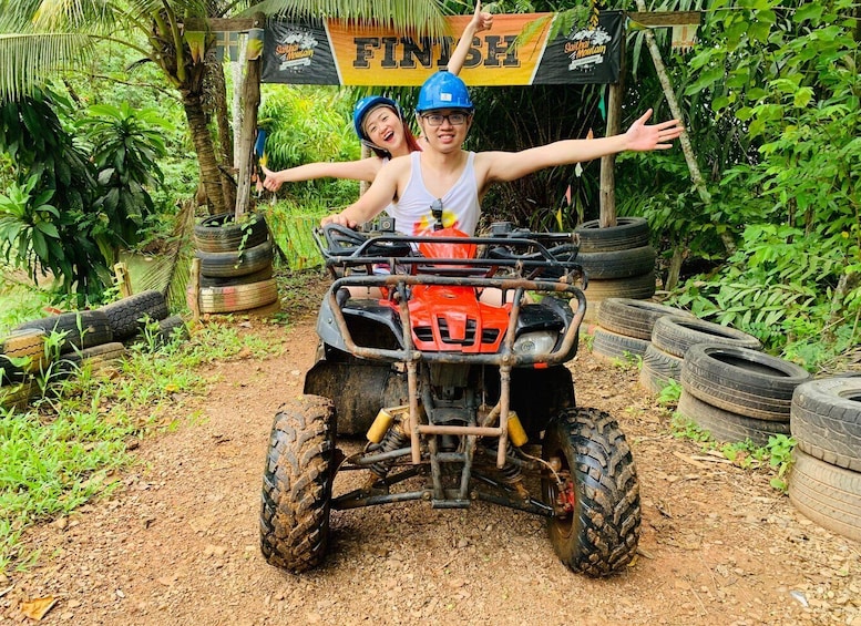 Two people on a red ATV with a 'FINISH' sign in the background. 2
