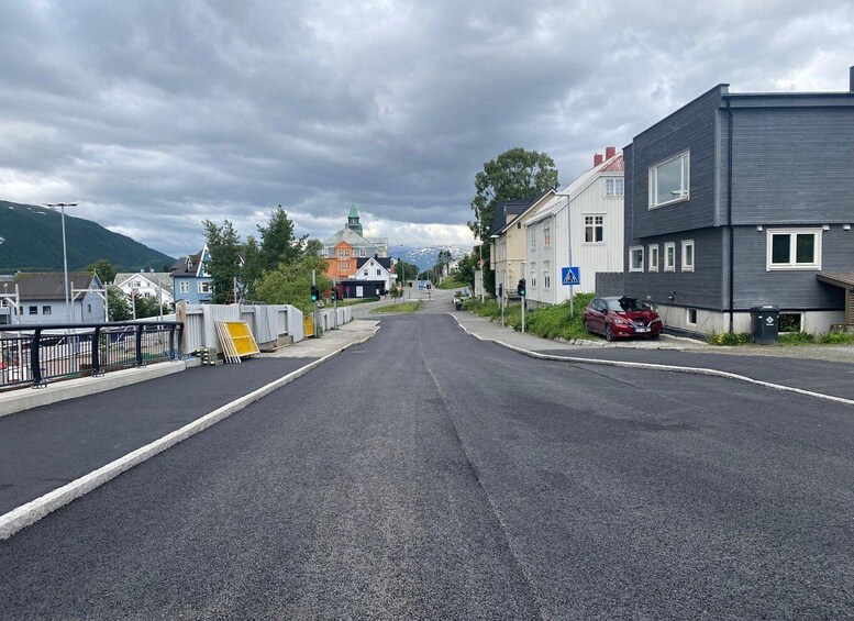A road with buildings on both sides, a pedestrian crossing sign, and a car parked on the right. 2
