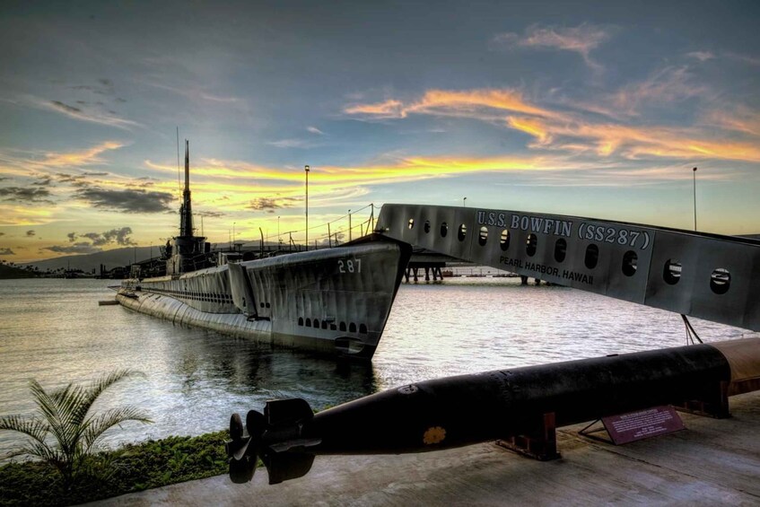 A U.S.S. Bowfin (SS287) anchored at Pearl Harbor, Hawaii, with a sunset sky and a pier extending into the water. 1