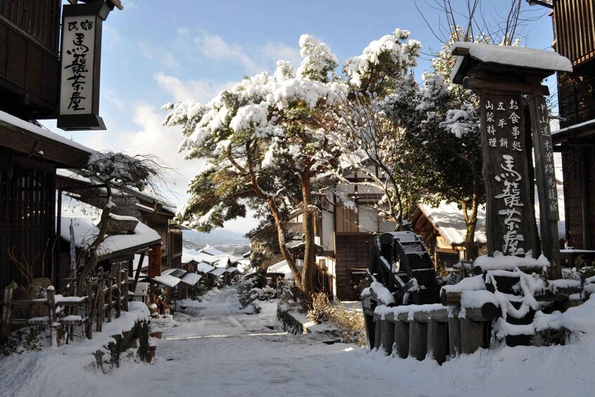 A snow-covered street with traditional Japanese buildings and signage. 3