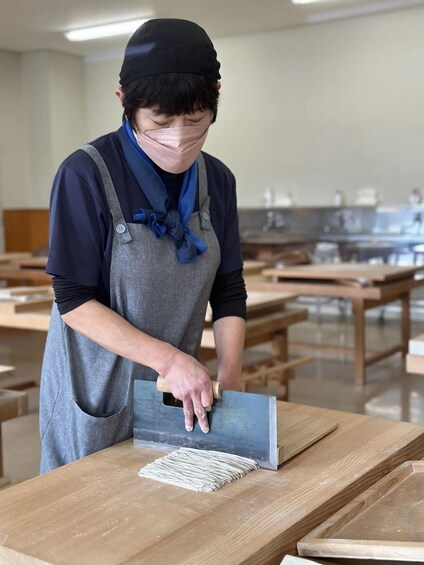 A person using a trowel on a wooden surface in a workshop. 5
