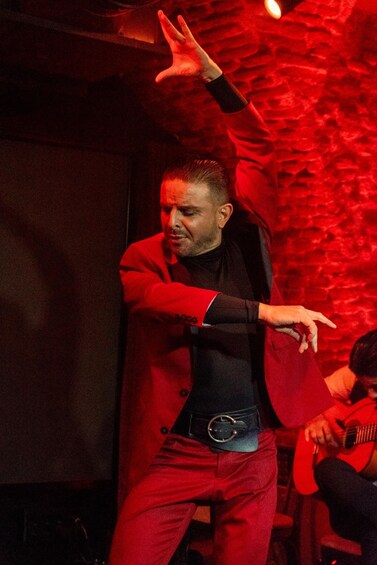 A person in a red coat and black shirt performing on stage. 3