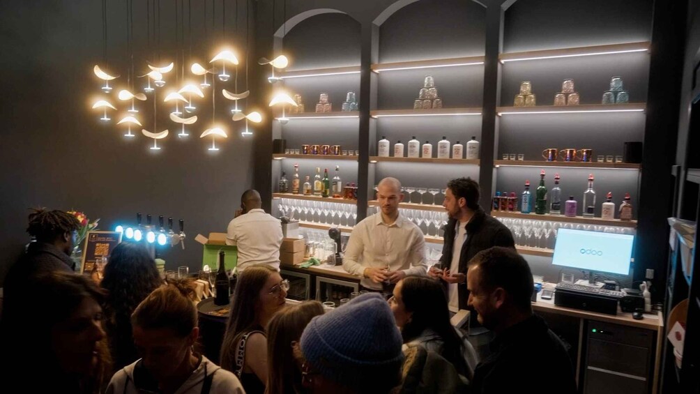 A bar with people conversing, shelves with bottles, and a digital screen displaying 'odoo'. 2