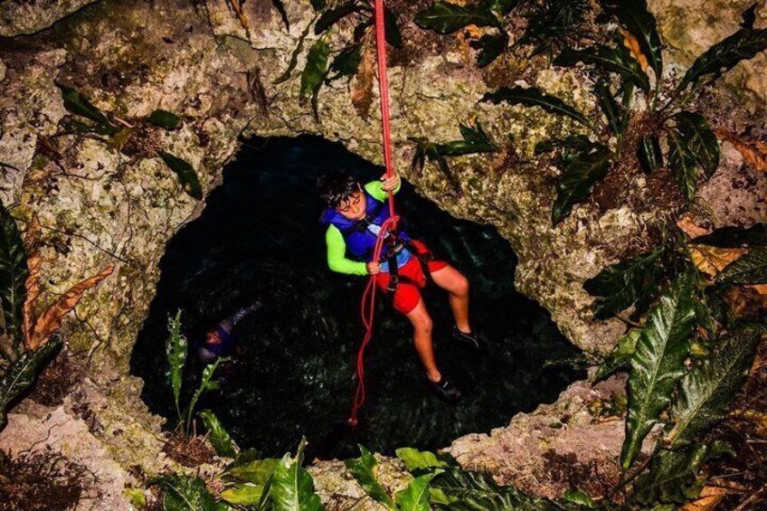 A person rappelling down a rocky cliff with vegetation around. 2