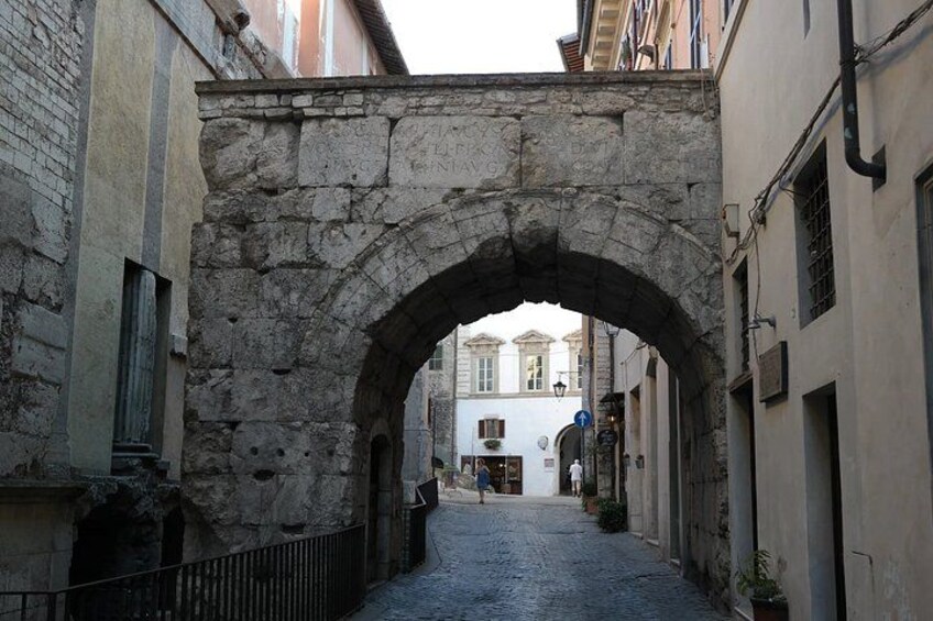 A stone archway in a narrow street with buildings on either side. 4