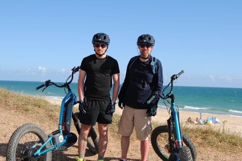 Two people standing on a beach with bicycles. 2