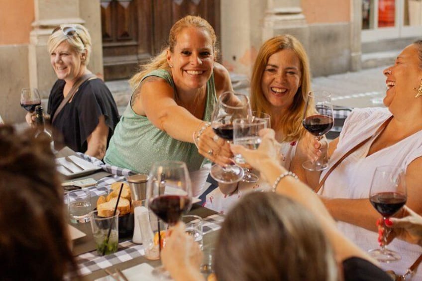 A group of people toasting with wine glasses at a table with bread and a candle. 2