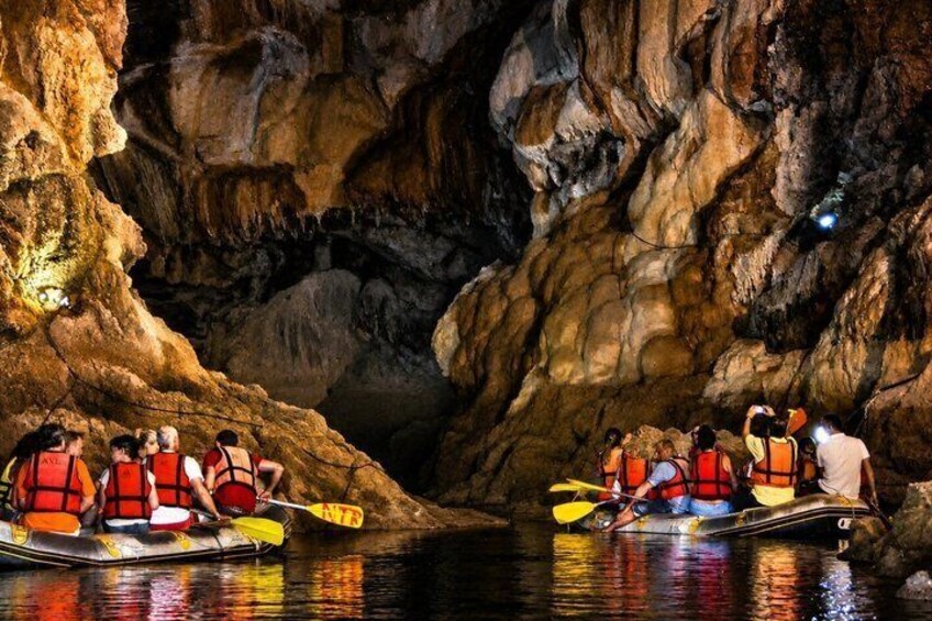 A group of people kayaking in a cave with rocky walls. 3