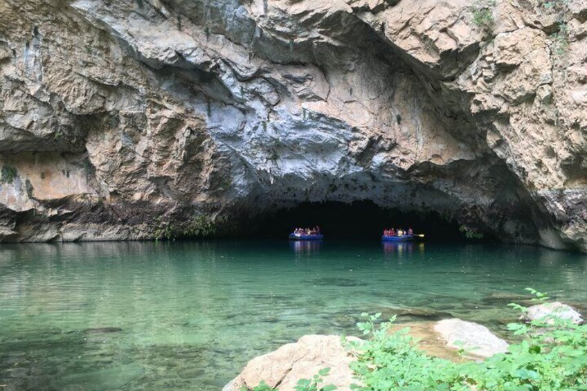 A cave entrance with clear water and two boats inside. 2