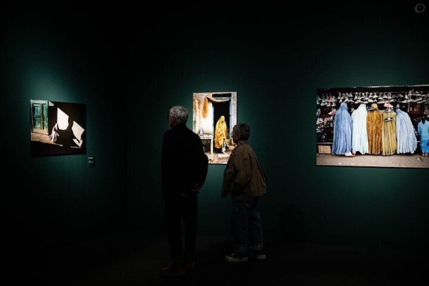 An art gallery with three illuminated paintings on the wall. 4