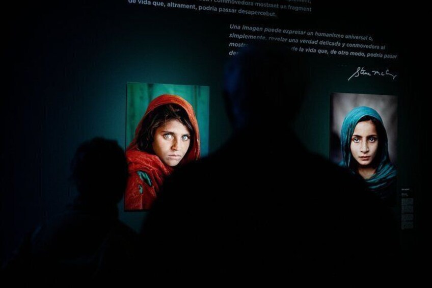A dark room with two portraits on the wall, one with a red garment and the other with a blue garment. 3